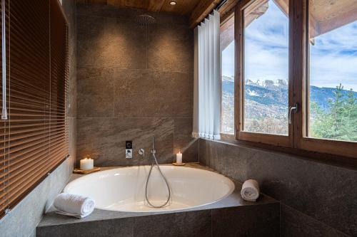 Un baño con bañera con dos velas y una ventana. en Chalet La Louvetiere 14 persones 6 chambres, en Le Bez