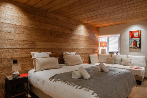 Dos camas en un dormitorio con una pared de madera. en Chalet La Louvetiere 14 persones 6 chambres, en Le Bez
