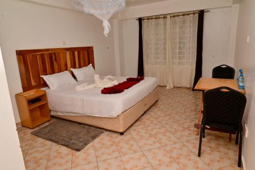 Un dormitorio con una cama grande y una silla. en Snow Peak Hotel in Chogoria, en Mwangarimwe