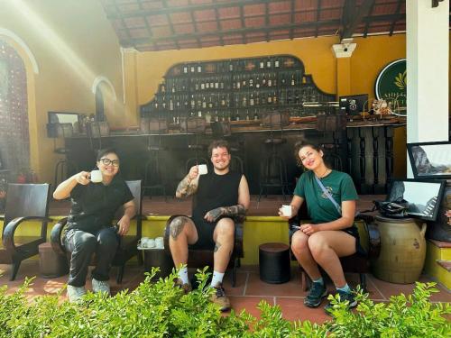 Un grupo de tres personas sentadas en una habitación con bebidas. en ANN GARDEN RETREAT Cat Ba, en Cat Ba