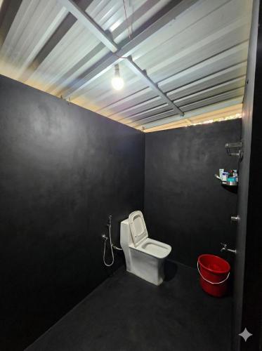 a bathroom with a toilet and a red bucket at The Kadu in Tāzhekkod