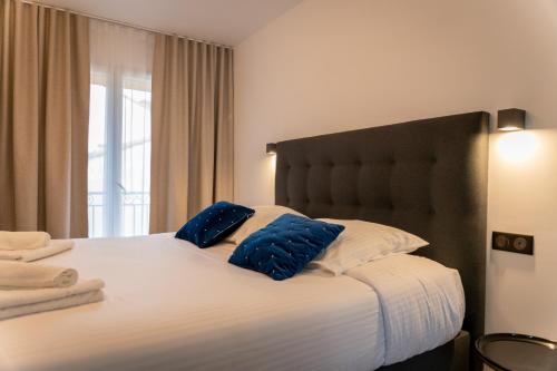 Superbe Appartement - Centre Mandelieu في ماندوليو لا نابول: غرفة نوم بها سرير كبير عليه وسائد زرقاء
