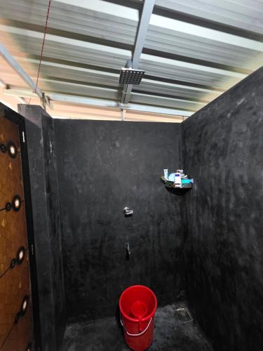 een badkamer met een rode emmer in een kamer bij The Kadu in Tāzhekkod