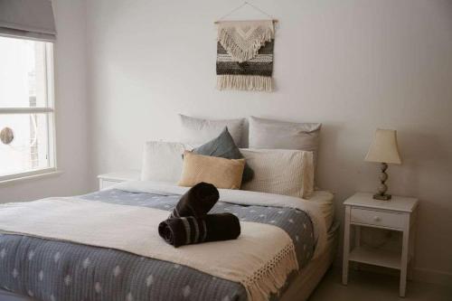 a bed with a hat on top of it in a bedroom at Neptunes Guest House in Port Campbell