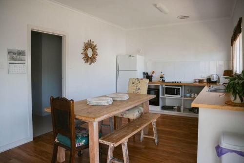 a kitchen with a wooden table with chairs and a refrigerator at Neptunes Guest House in Port Campbell