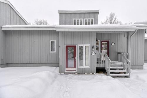 een grijs huis met rode deuren in de sneeuw bij Pool Table - Elegance - Comfort - Le Chic Boreal in Saint-Jovite