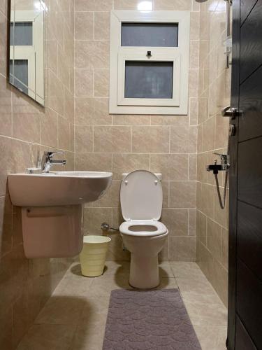 a bathroom with a toilet and a sink and a window at The Address Modern apartment in Sheikh Zayed