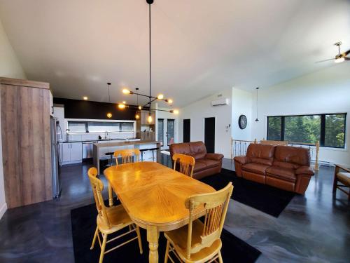 a kitchen and living room with a wooden table and chairs at Relaxation & Comfort - Chalet Sault a la Puce in Sainte-Anne-de-Beaupré