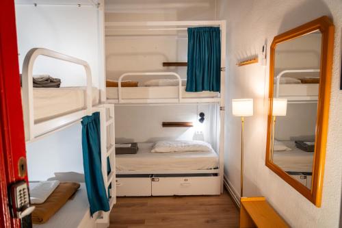 Una pequeña habitación con dos literas y un espejo. en Soul Backpackers Barcelona, en Barcelona