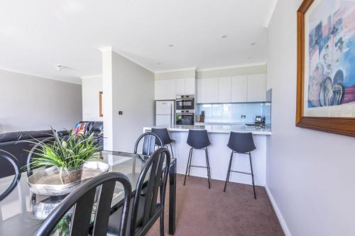 モリーモックにあるFathoms 2 - 2BR beach resort apartmentのダイニングルーム、キッチン(ガラスのテーブル、椅子付)