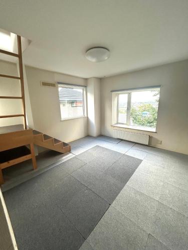 an empty room with a staircase and two windows at Nature Moiwa in Sapporo
