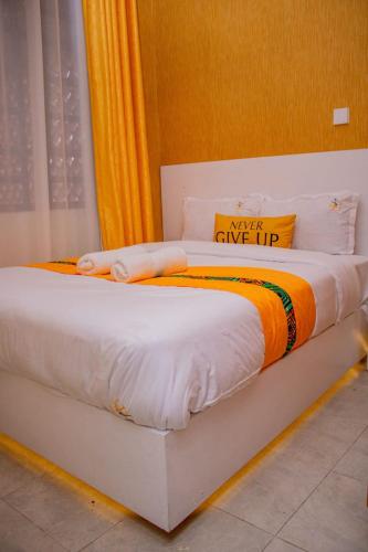 a white bed with an orange and white blanket at Yellow Petals Homestays in Nanyuki
