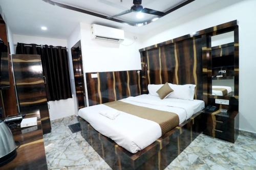 Best Buy Hotel في كولْكاتا: غرفة نوم بسرير كبير مع لوح رأس خشبي