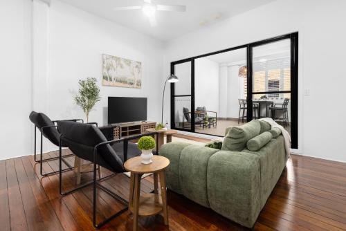 a living room with a green couch and black chairs at Spacious 3BR Heritage Apartment with Pool, Parking in Brisbane