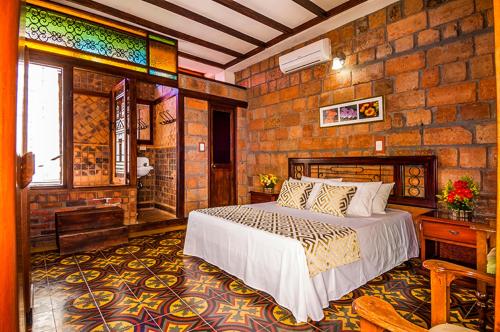 a bedroom with a bed and a brick wall at Hosteria de la Plaza Menor in Santa Fe de Antioquia