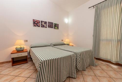 a bedroom with a bed and a table with two lamps at Rosmarino veranda and pool with sunset view in Costa Paradiso