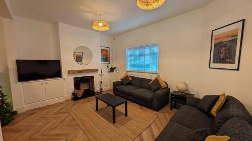 a living room with a couch and a television at Welcome to the Cobbler's at Barry Island in Barry