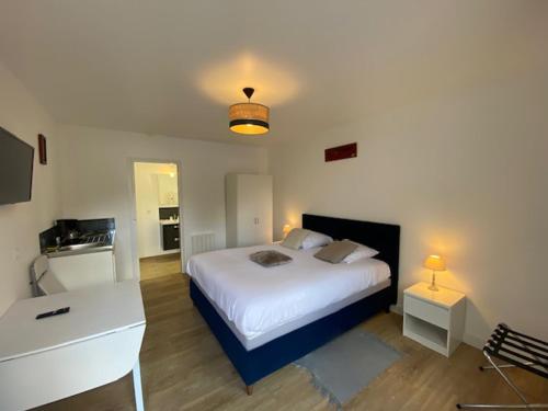 a bedroom with a large white bed and a desk at B&B de Saint Come de Fresné in Saint-Côme-de-Fresné