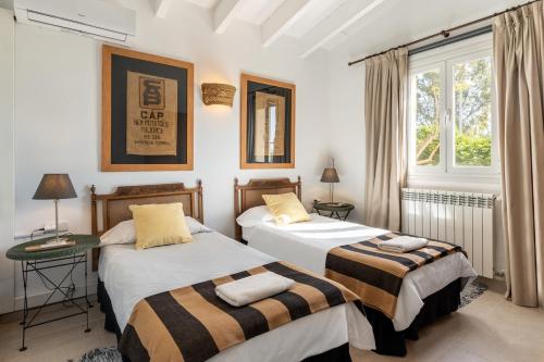 twee bedden in een kamer met een raam bij Villa Portol in Pòrtol