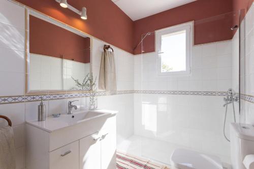 een badkamer met een wastafel, een toilet en een spiegel bij Villa Portol in Pòrtol