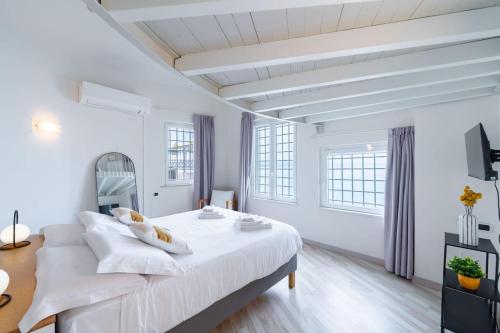 a white bedroom with a large bed and windows at Villa Aquarium in Desenzano del Garda