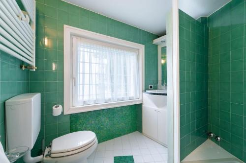 a green bathroom with a toilet and a window at Villa Aquarium in Desenzano del Garda