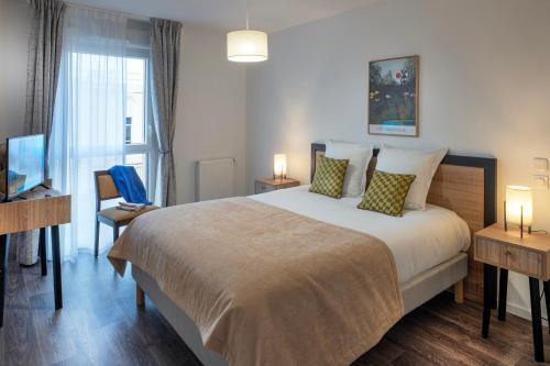 a bedroom with a large bed and a television at DOMITYS - La Florentine in Sarreguemines
