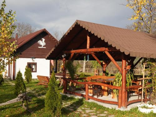 a wooden pavilion with tables and benches in a yard at Pensiunea Cocoș in Spulber