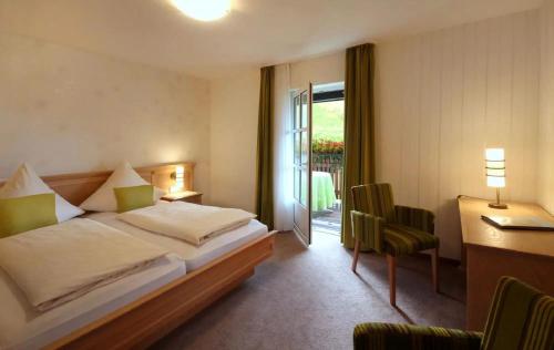 a bedroom with a bed and a desk and a window at Lauras - Landhauspension in Medebach