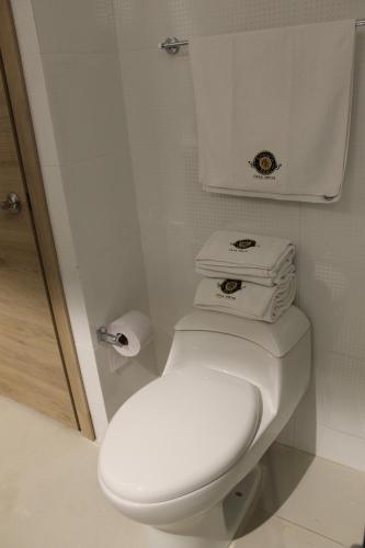 a bathroom with a white toilet with two stacks of towels at Casa Hotel Boyaca Real in Bogotá