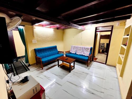Una sala de estar con dos sofás azules y una mesa. en Edwin and Edrin Service Villa, en Wayanad