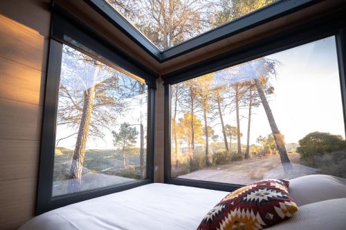 a bedroom with a large window with a view of a forest at Cabañas en el bosque cerca de Barcelona in Talamanca