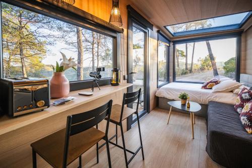 a bedroom in a tiny house with a large window at Cabañas en el bosque cerca de Barcelona in Talamanca