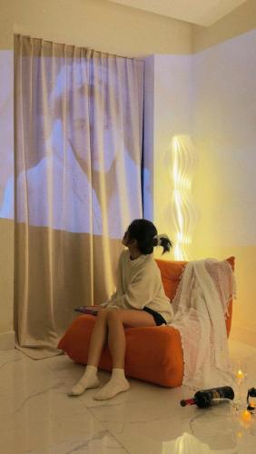 a woman sitting on a bed in front of a window at Huế Nestory Homestay in Thôn Trường Giang