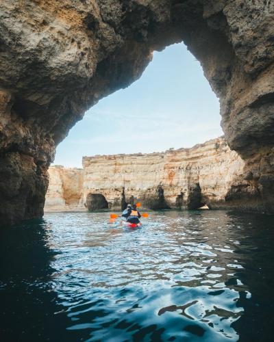 a person kayaking through a cave in the water at HolaCamp Albufeira in Albufeira