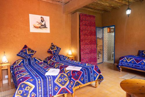 um quarto com 2 camas e cobertores coloridos em La Maison de l'Homme Bleu em Aït Boukha
