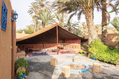uma tenda com mesa, cadeiras e palmeiras em La Maison de l'Homme Bleu em Aït Boukha
