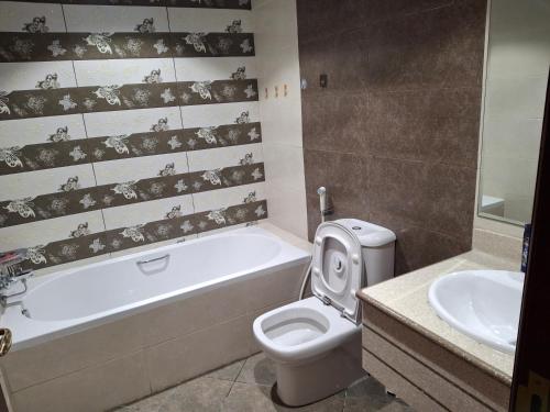 a bathroom with a toilet and a tub and a sink at luxury apartment 2 Bedroom and Big Hall in Ajman