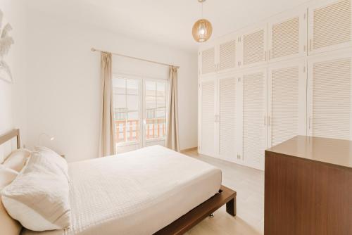 a white bedroom with a bed and a window at Apartment Old Town Reina Sofia 1 in Puerto del Carmen