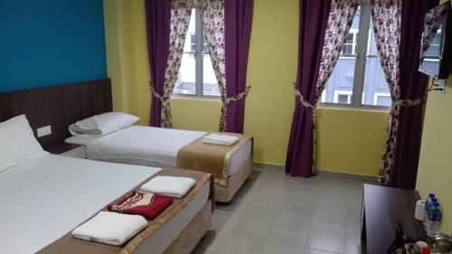 a hotel room with two beds and two windows at Casa D'rose Hotel in Malacca
