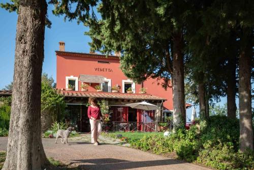 a woman walking a dog in front of a building at Be Vedetta - Relais & Glamping - Adult Only in Scarlino