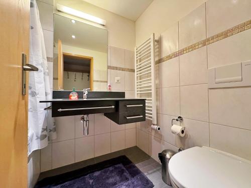 Un baño con lavabo, inodoro y espejo. en Eiger Residence 3, en Wengen