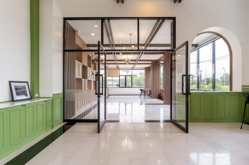 an open door in a building with green walls and a hallway at Finn Hotel in Ban Fang Daeng