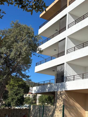 an apartment building with balconies and a tree at A Isula Paradisu - Classé 4 étoiles in LʼÎle-Rousse