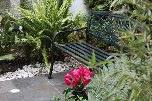 a black bench in a garden with pink flowers at Casa Hotel Boyaca Real in Bogotá