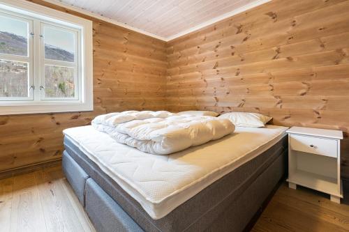 ein großes Bett in einem Zimmer mit einer Holzwand in der Unterkunft Stranda Fjellgrend 3 bedrooms and loft - 80D in Stranda