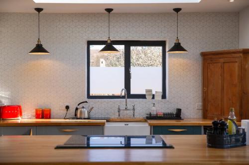 a kitchen with three pendant lights above a wooden table at Oxfordshire Country Escape, 3 Bed Getaway in Long Wittenham