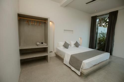 a white bedroom with a bed and a window at Nico Villa in Ahangama