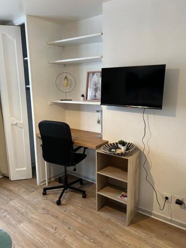 a desk with a chair and a television on a wall at Studio - Le Bourgogne 21 in Orléans