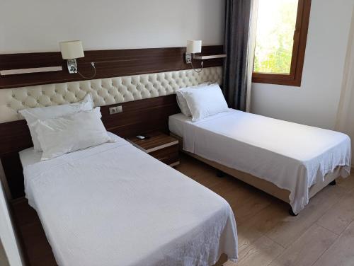 Una habitación de hotel con dos camas y una ventana. en Manuela Boutique Hotel Bitez, en Bitez